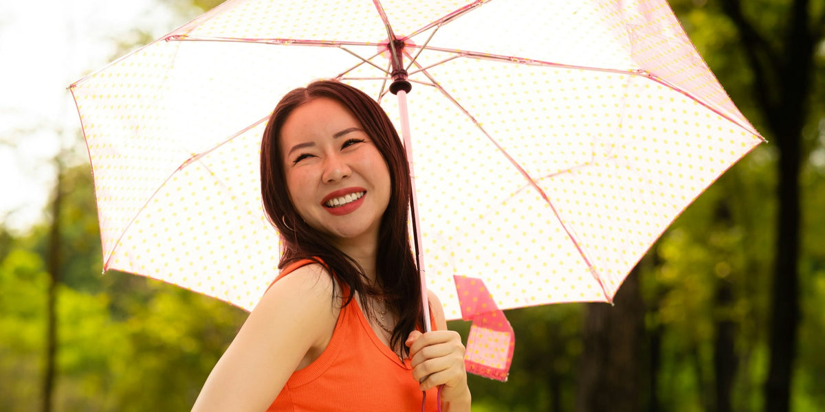 A photo of a happy woman outdoors holding an umbrella